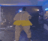 a person in a yellow dress is dancing in a room with purple lights .