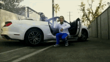 a man in blue pants sits in a white car