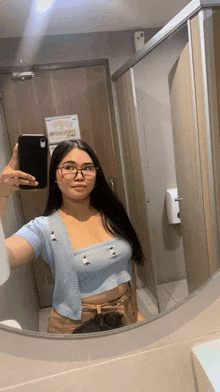 a woman taking a selfie in front of a mirror in a bathroom