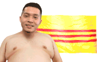 a shirtless man smiles in front of a yellow and red flag