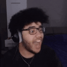 a man with a beard and glasses is wearing headphones and making a funny face .