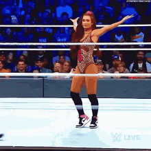 a woman is dancing in a wrestling ring while a crowd watches .