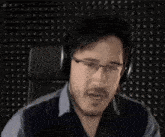 a man wearing headphones is making a funny face while sitting in front of a microphone .