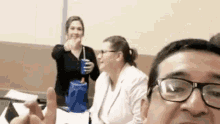 a man with glasses is taking a selfie with two women .