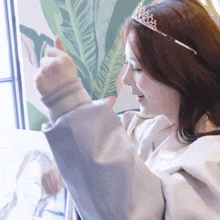 a woman wearing a tiara is giving a thumbs up sign