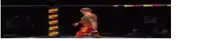 a man in red shorts is standing in a boxing ring with his arms outstretched .