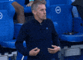 a man wearing a blue shirt with the word eagle on it stands in front of blue chairs