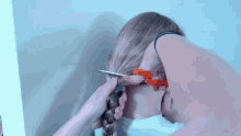 a person is cutting a woman 's hair with a pair of scissors