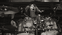 a woman is playing a drum set with the letter d on the bottom