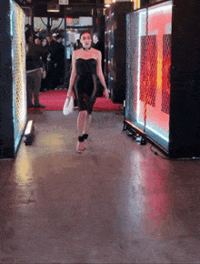 a woman in a black dress is walking down the red carpet
