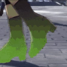 a close up of a person 's feet in green boots walking on a brick sidewalk .