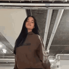a woman in a brown hoodie is standing in a room .
