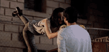 a man and a woman kissing in front of a brick wall
