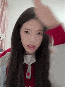a girl with long black hair wearing a red shirt with a red button