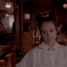 a woman wearing a white shirt and a bow tie looks at the camera