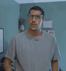 a man with glasses and a mustache is wearing a grey shirt .
