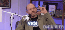 a man sitting in front of a microphone with the words dark web on the bottom right