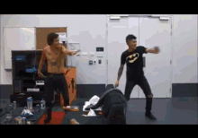 two men are dancing in a room with one wearing a batman t-shirt