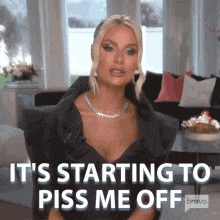 a woman in a black dress is sitting in a chair and says it 's starting to piss me off