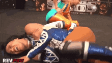 two women wrestling in a ring with rev pro written on the bottom right