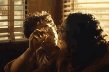 a man and woman are kissing in front of a window with blinds on it
