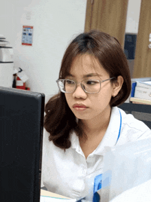 a woman wearing glasses sits in front of a computer