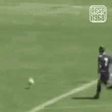 a soccer player is running towards a goal while another player watches .