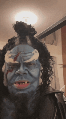 a person with blue paint on their face and a wig