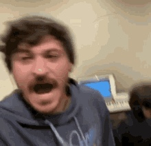a blurry picture of a man with his mouth open wearing a blue hoodie that says ' nc ' on it