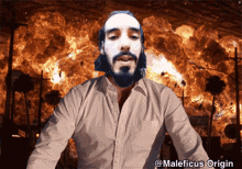 a man with a beard is standing in front of an explosion with the words maleficus origin written below him