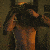 a shirtless man stands in a dark room