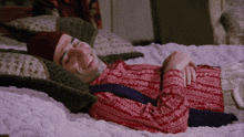 a man in a red sweater is laying on a bed smiling