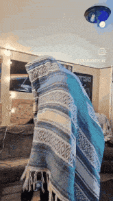 a blue and white blanket covering a person 's head in a room