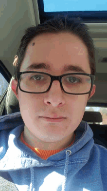 a man wearing glasses and a blue hoodie looks at the camera