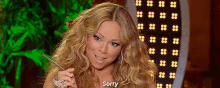 a woman with long blonde hair is sitting in front of a green screen and says `` sorry '' .