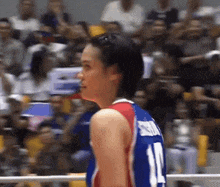 a woman wearing a jersey with the number 11 on it stands in front of a crowd