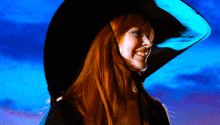a woman with red hair is wearing a large black hat