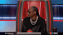 snoop dogg sits in a chair with a nbc logo in the background