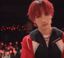 a young man with red hair is wearing a red jacket and a black vest .
