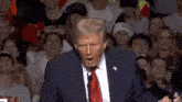 donald trump is giving a speech in front of a crowd that is laughing and cheering