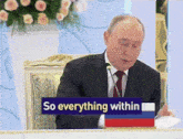 a man in a suit and tie sits at a table with a sign that says " so everything within "