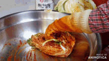 a person wearing orange gloves is holding a large piece of food in a bowl that says made in animatica