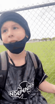 a young boy wearing a mask and a tie dye shirt is sitting on a bench .