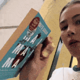 a woman is holding a book that says " ma ma " on the cover