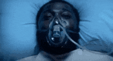 a man is wearing an oxygen mask in a hospital bed .
