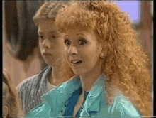 a woman with red curly hair is wearing a blue jacket and earrings