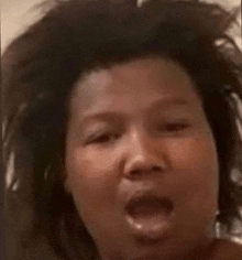 a close up of a person 's face with their mouth open and their hair blowing in the wind .