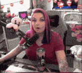 a woman with purple hair is sitting in front of a microphone in a room .