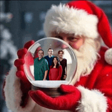 santa is holding a snow globe with a picture of his family in it