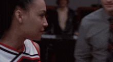 two cheerleaders are looking at each other with a man in a suit behind them